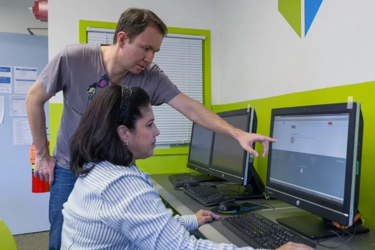 A man shows a woman something on a computer screen.