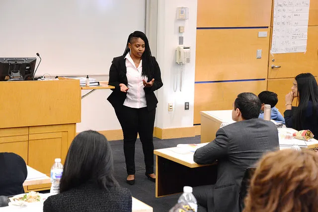 A woman in a suit makes a presentation to a classroom.