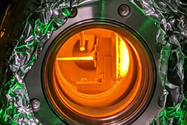 Cooling in progress. A beam of sodium atoms glows orange as they re-emit photons after being struck by a laser beam.