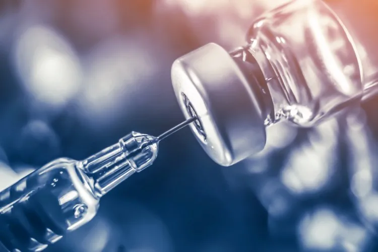 A syringe being stuck into a vial.